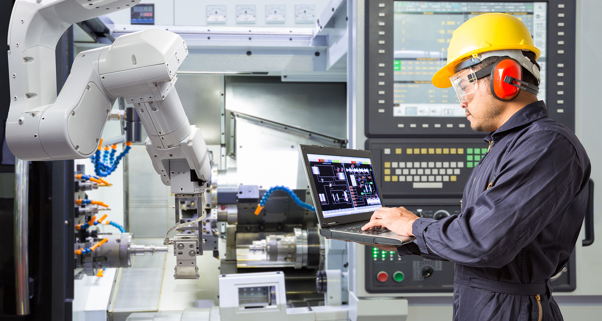 Operator using a laptop to monitor or control a robot in a production line
